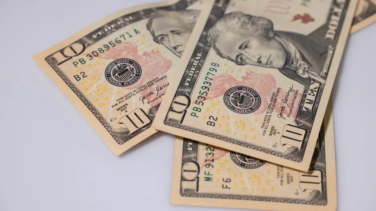 Detailed view of American ten dollar bills scattered on a light surface, showcasing currency features.