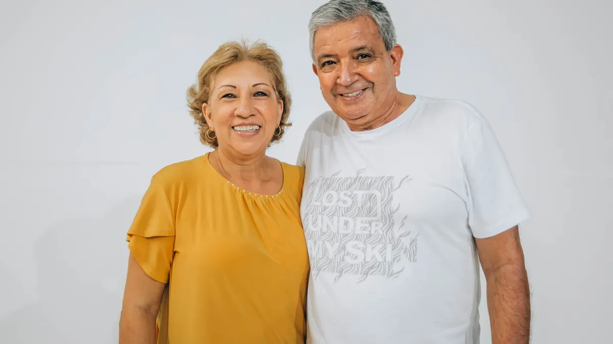 Happy elderly couple smiling in a portrait with a white background.