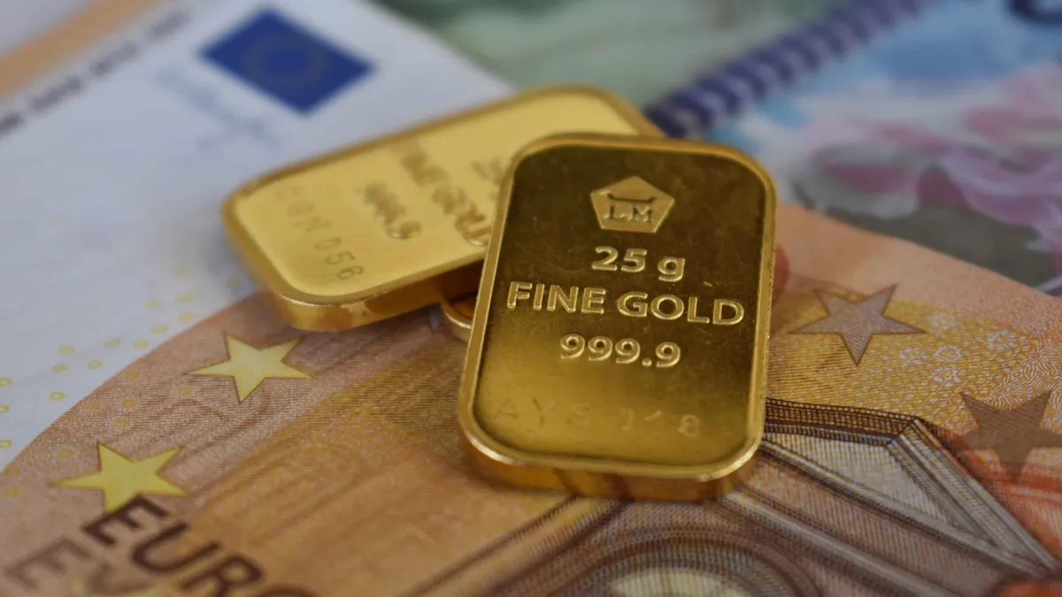 Detailed view of gold bullion bars placed on European currency euro banknotes, symbolizing wealth and investment.