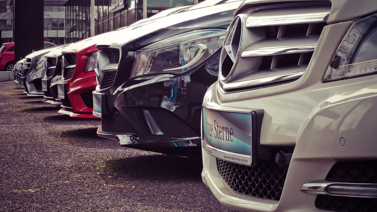 Luxury cars lined up at an outdoor dealership, showcasing sleek designs.