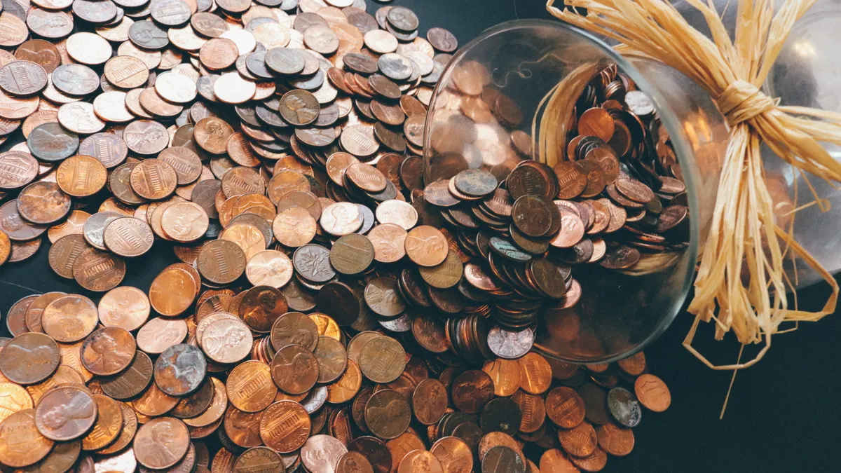 Spilled jar of pennies creating a pattern of coins representing savings and finance.