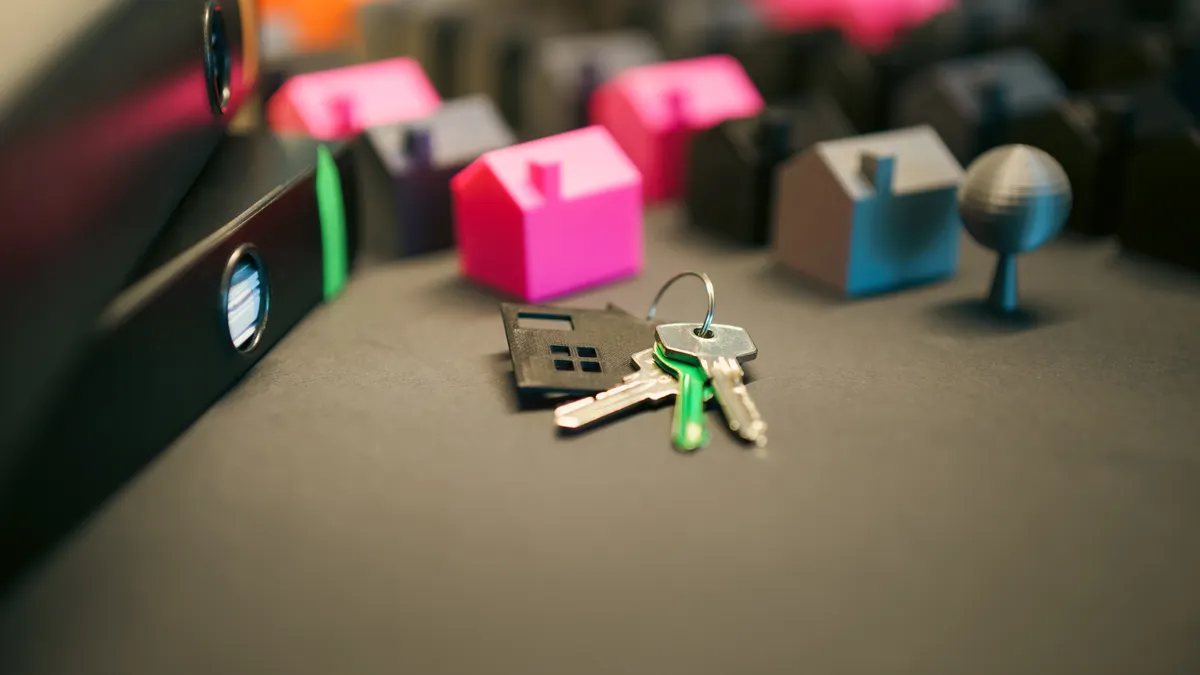 Miniature model houses and keys on a desk, symbolizing real estate and property investment.
