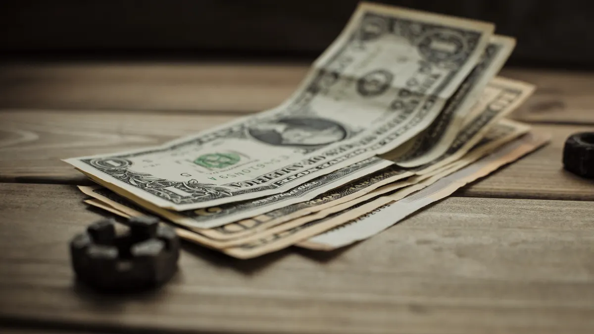 Close-up of US dollar bills on a wooden table, representing finance and commerce.