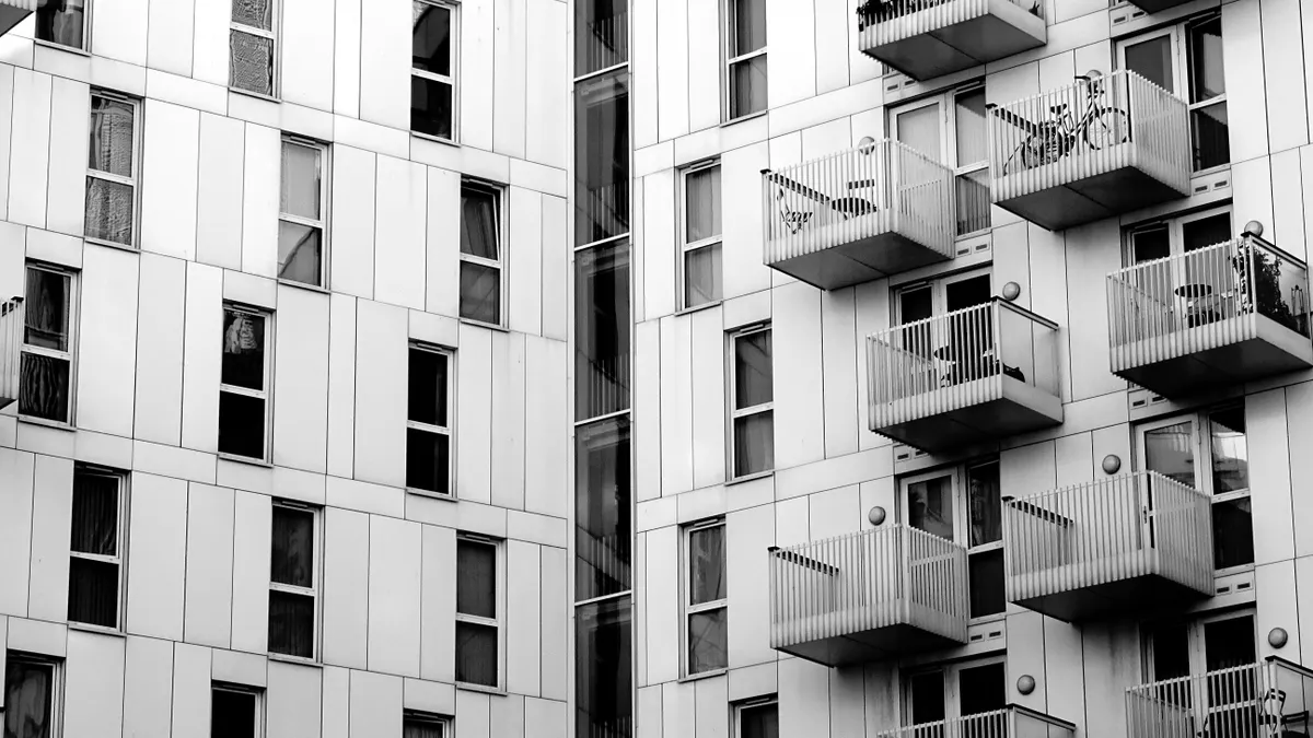 Black and white photo of modern high-rise apartments with multiple balconies.