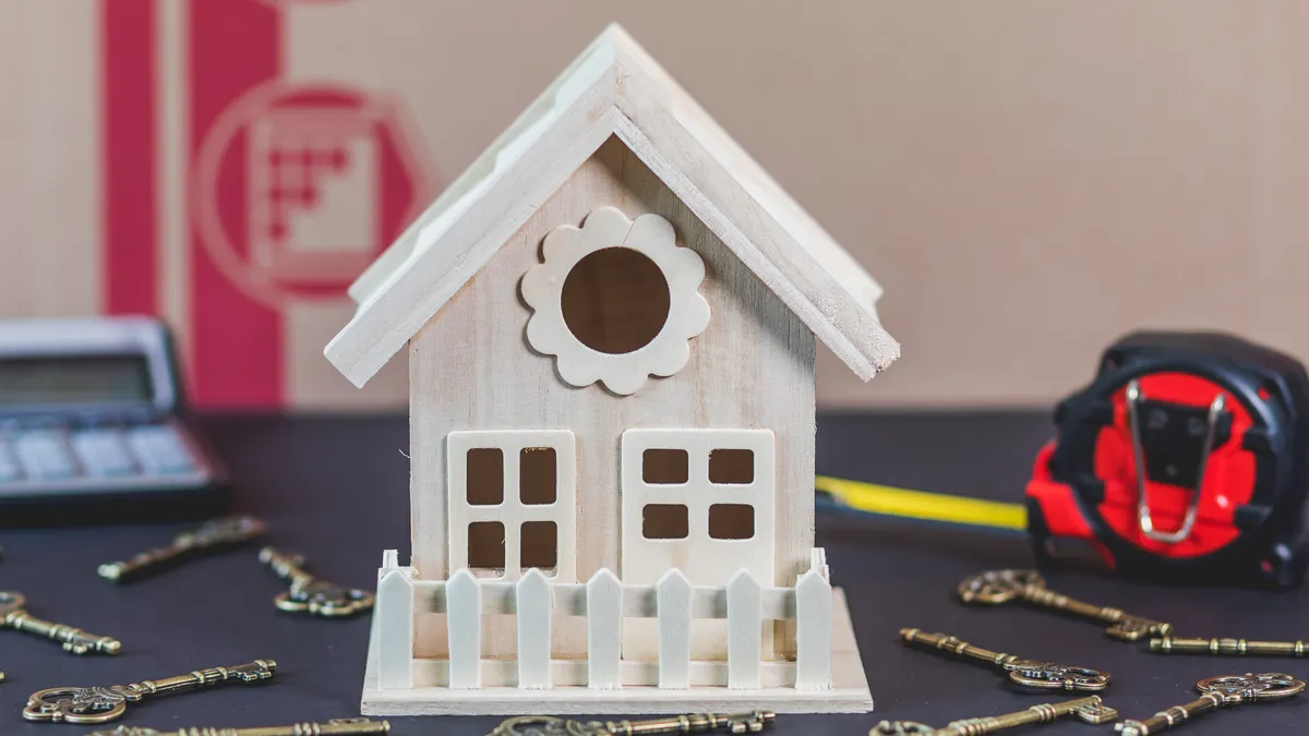 A charming wooden miniature house surrounded by antique-style keys, ideal for concepts of home ownership.