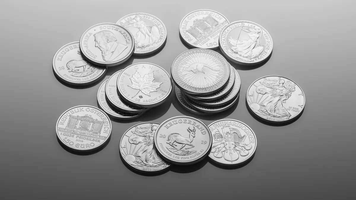 A close-up of various silver bullion coins, showcasing intricate designs on a reflective surface.