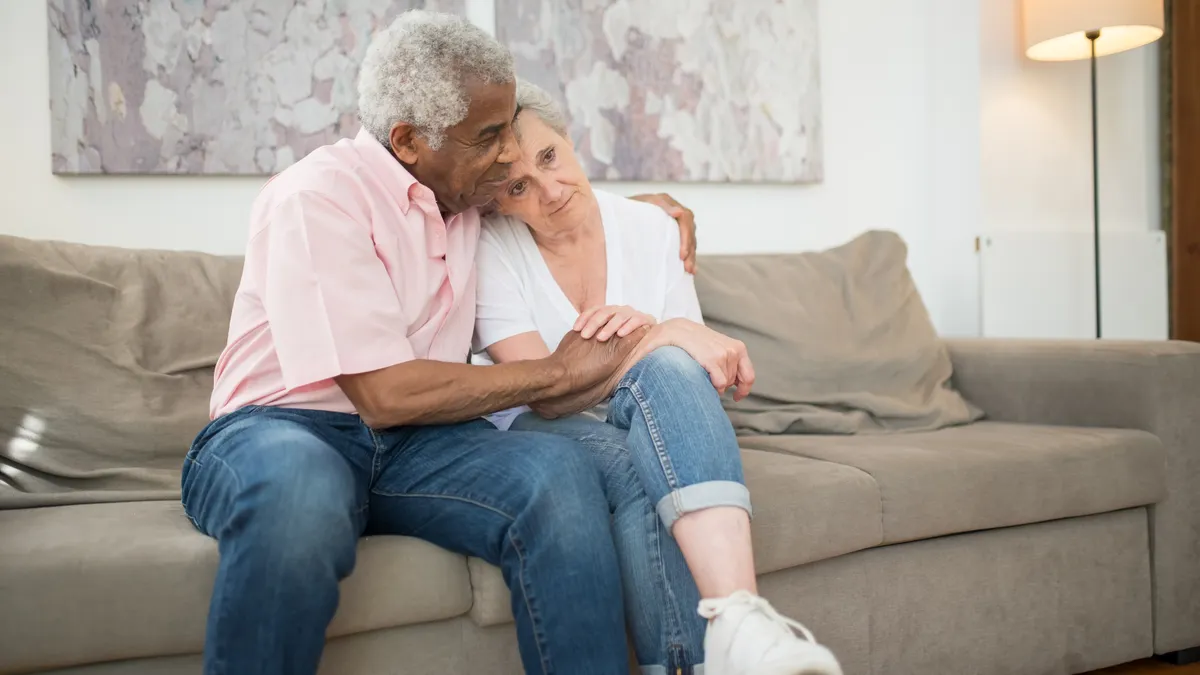 Senior couple embracing warmly on a sofa at home, showcasing love and togetherness.