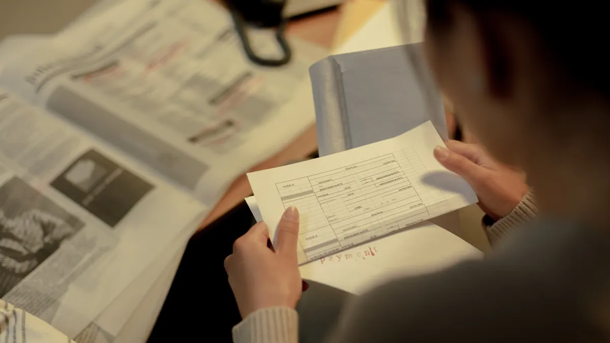 Adult woman reading a questionnaire and job postings indoors at a table, focused and contemplative.